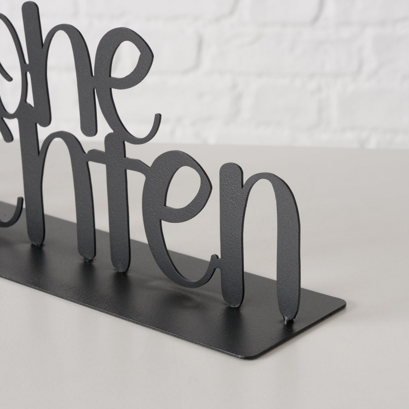 Schwarzer metallener Schriftzug „Frohe Weihnachten“ als dekorativer Aufsteller im modernen, matten Design Detail bild